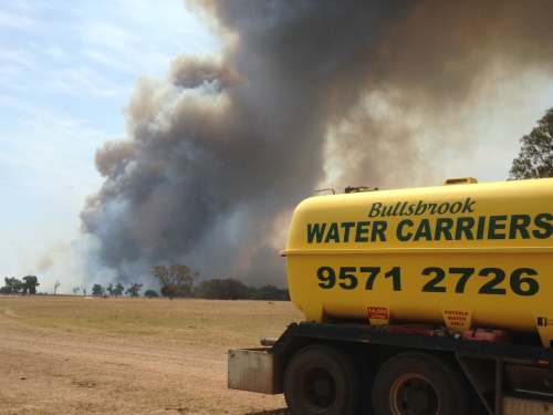 Water truck with smoke from bushfire billowing in the background